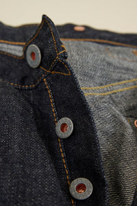 Graph Zero Heritage Denim - 13oz close-up of embossed metal buttons and selvedge denim fabric details.