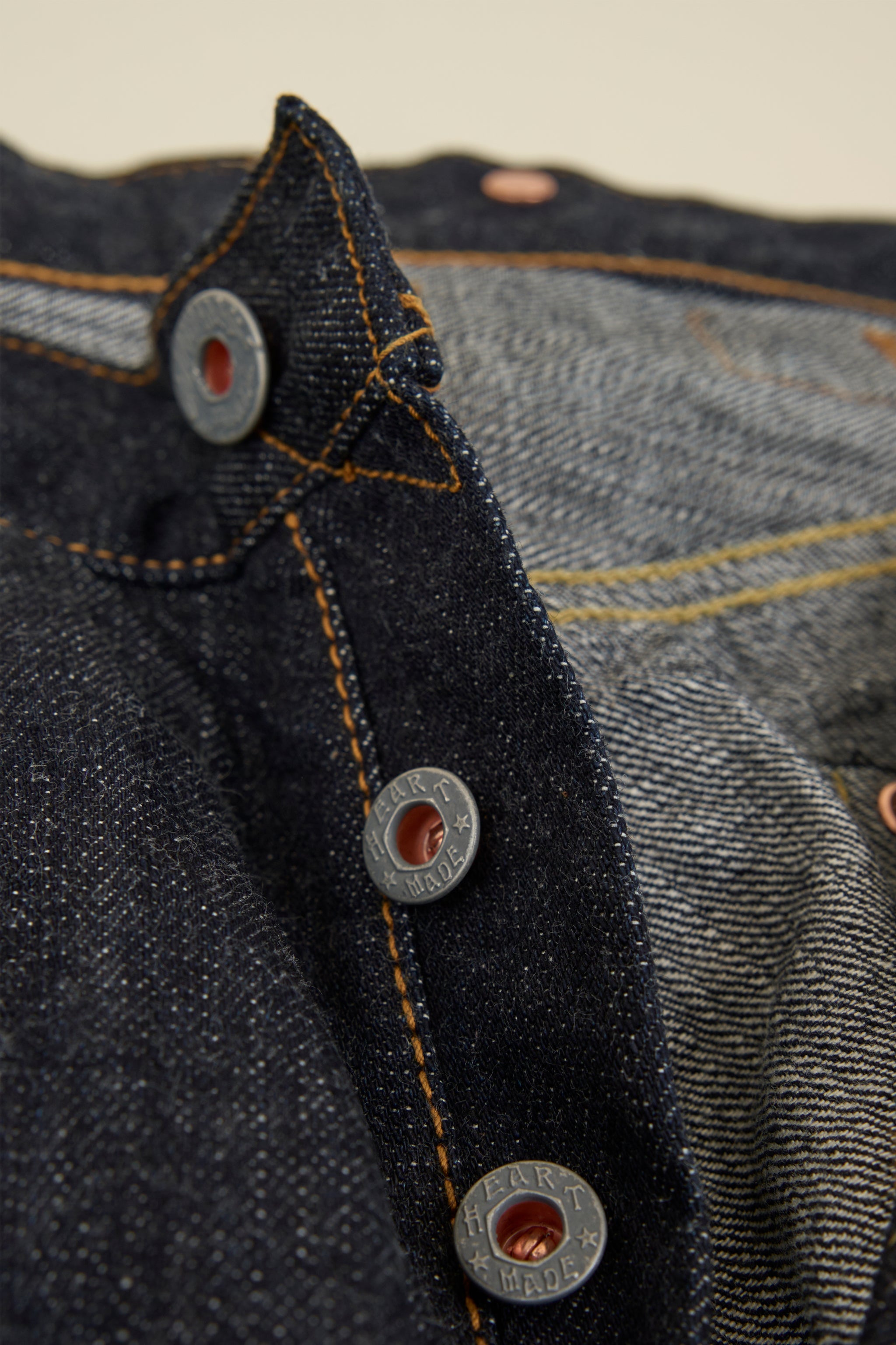 Graph Zero Heritage Denim - 13oz close-up of embossed metal buttons and selvedge denim fabric details.